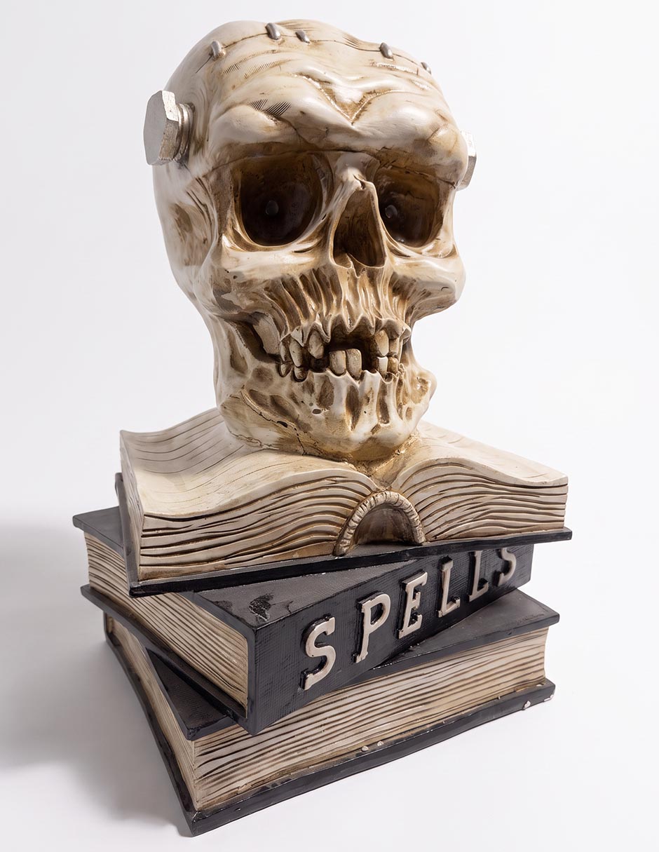 Figura decorativa de halloween con forma de cráneo sobre libros 1